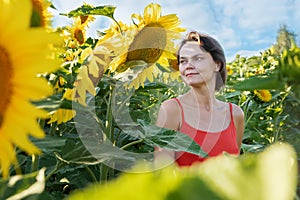 Beautiful young woman with sunflowers enjoying nature and laughing on summer sunflower field. Woman holding sunflowers