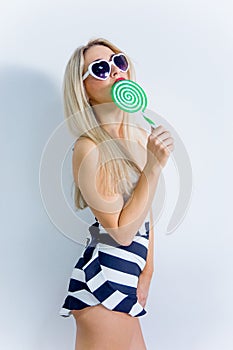 Beautiful young woman in sunglasses with a lollipop