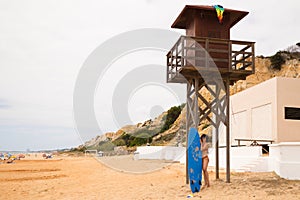 Beautiful young woman with a surfboard on the beach. The woman holds the surfboard while doing postures. The woman is standing