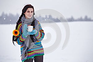 Beautiful young woman in a sweater on a winter walk with a cup o