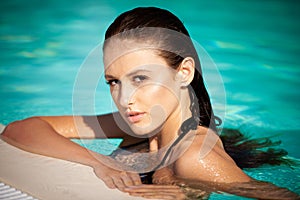 Beautiful young woman swimming in the pool on a hot summer day