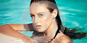 Beautiful young woman swimming in the pool on a hot summer day