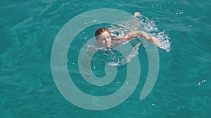 Beautiful young woman swims in clear blue water near Formentera or Ibiza islands around luxury yach. Slow motion