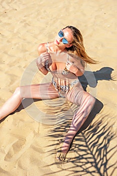 Beautiful young woman in swimsuit posing on a sand beach. Summer holiday concept