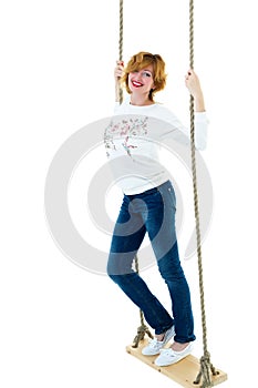 Beautiful young woman on a swing against white studio backgroun