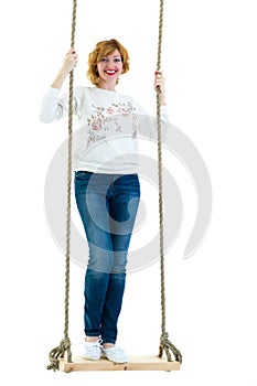 Beautiful young woman on a swing against white studio backgroun