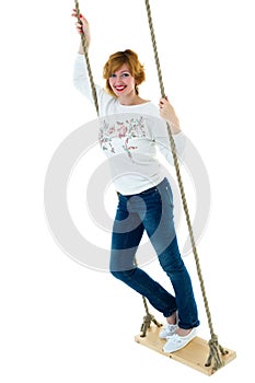 Beautiful young woman on a swing against white studio backgroun