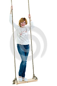 Beautiful young woman on a swing against white studio background.
