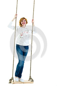 Beautiful young woman on a swing against white studio background.