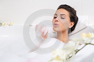 Beautiful young woman takes bubble bath