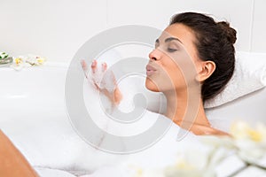 Beautiful young woman takes bubble bath