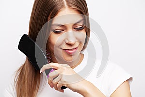 Beautiful young woman takes care of her hair, combing long hair with a comb