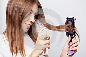Beautiful young woman takes care of her hair, combing long hair with a comb