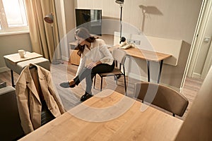 Beautiful young woman takes off her shoes while sitting on chair