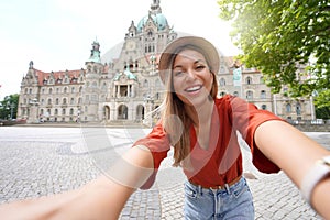 Beautiful young woman takes selfie photo in front of Hanover city hall, Germany