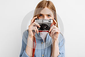 Beautiful young woman taking photo on retro camera isolated on white background