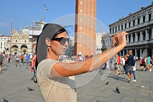 A beautiful young woman taking a photos with her smartphone in Venice