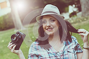 Beautiful young woman taking pictures in a park, light effect