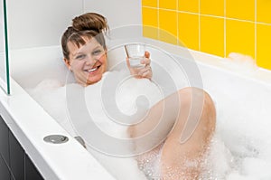 Beautiful young woman is taking relaxing bath with foam