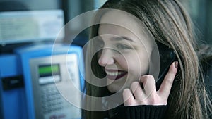 Beautiful young woman talking on payphone