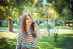 Beautiful young woman talking on phone in city