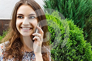 Beautiful young woman talking on a phone in city park