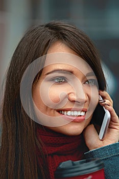 Beautiful young woman talking on phone and look straight ahead. Holding smartphone.