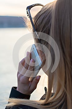 The Beautiful Young Woman is Talking on Phone with View on the City.