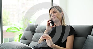 Beautiful young woman talking sitting on sofa at home and yawning