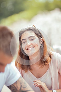 Beautiful young woman talking to somebody, outside in the sunlight, happy smiling