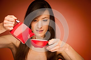 Beautiful young woman with tea pot and mug in her nhands photo