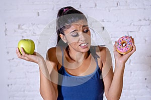 Attractive young woman on a diet deciding between an apple and a doughnut