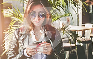 Beautiful young woman texting mesage on smartphone in cafe.