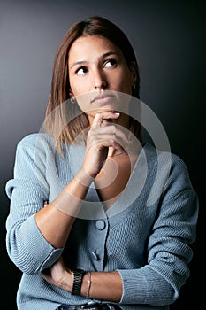 Beautiful young woman thinking on her worries over black background