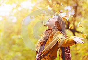 Beautiful young woman throwing leaves in a park