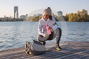 Beautiful young woman tired after working out outside drinking w