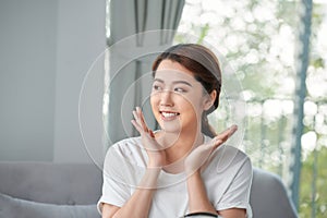 Beautiful young woman is touching her face and smiling while looking at the mirror