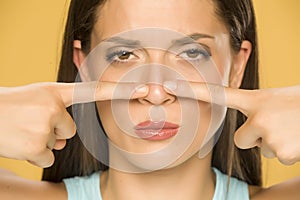 Beautiful young woman touching her nose with her fingers photo