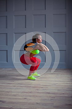 Beautiful young woman is training with a sandbag in the gym.