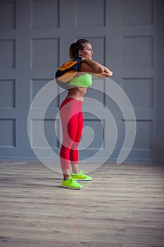 Beautiful young woman is training with a sandbag in the gym.