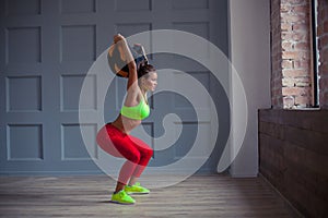 Beautiful young woman is training with a sandbag in the gym.