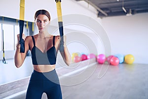 Beautiful young woman training with suspension trainer sling or