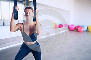 Beautiful young woman training with suspension trainer sling or