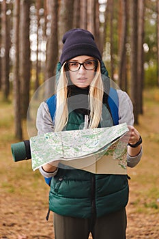 A beautiful young woman with travel map and backpack in pine plantations.