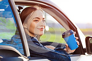 Beautiful young woman traveled on road in car, drinking coffee from disposable