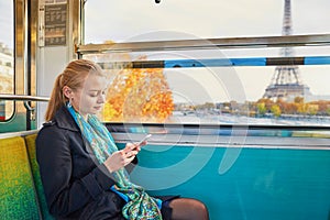 Beautiful young woman travelling in a train of Parisian underground and using her mobile phone