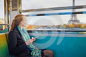 Beautiful young woman travelling in a train of Parisian underground and using her mobile phone