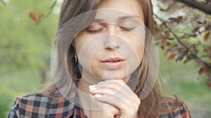 Beautiful young woman turns to God with feelings in prayer, the girl folded her arms at her chest and with gratitude looks at the