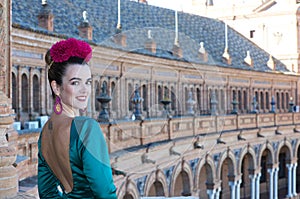 Beautiful young woman with typical green frilly dress and dancing flamenco in plaza de espana in sevilla, andalusia, she is on a photo