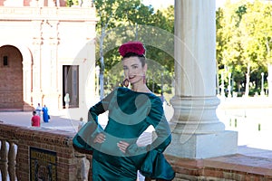 Beautiful young woman with typical green frilly dress and dancing flamenco in plaza de espana in sevilla, andalusia, she is on a photo